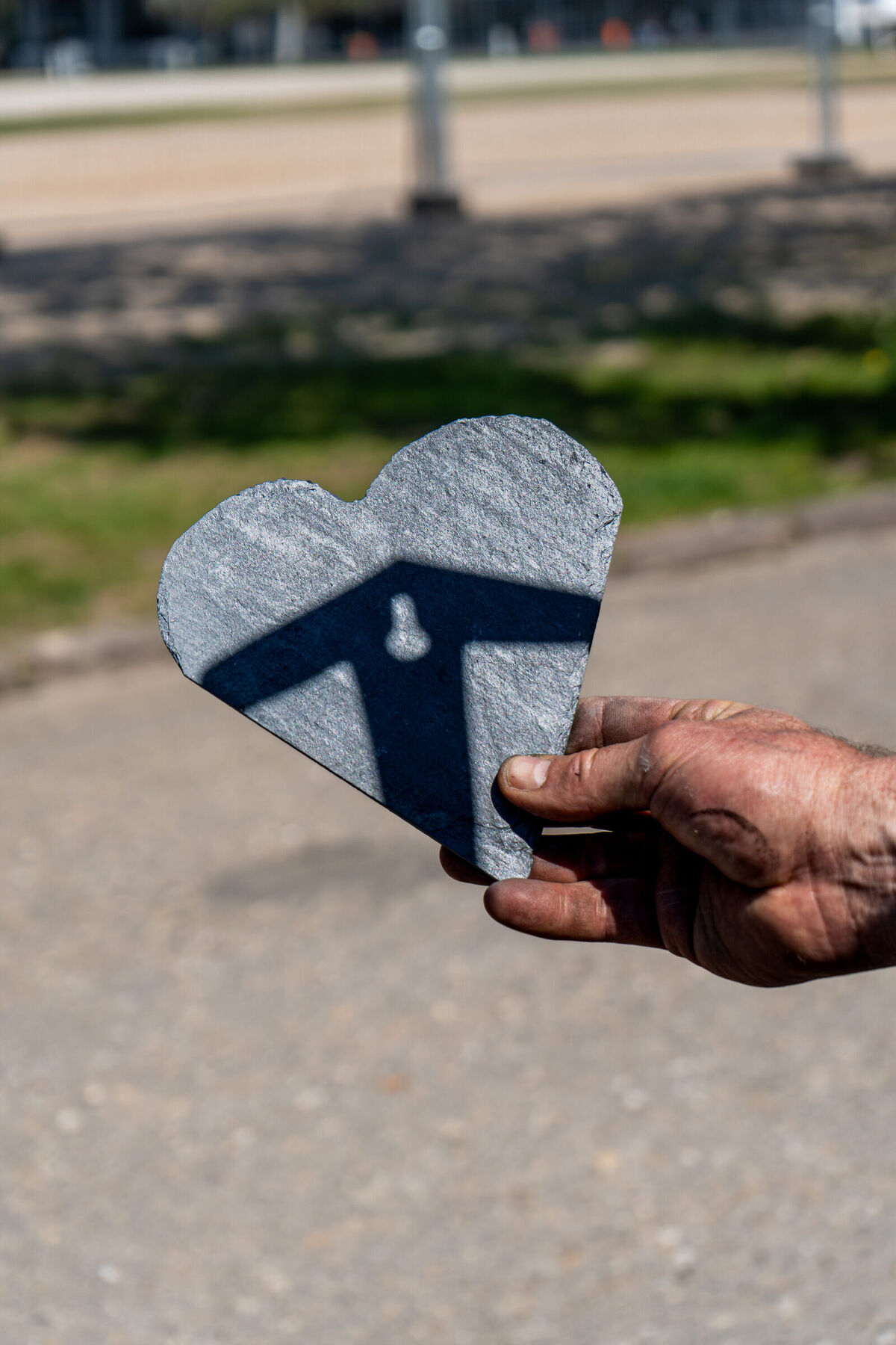 Schiefer-Herz mit Dach-Logo in der Hand